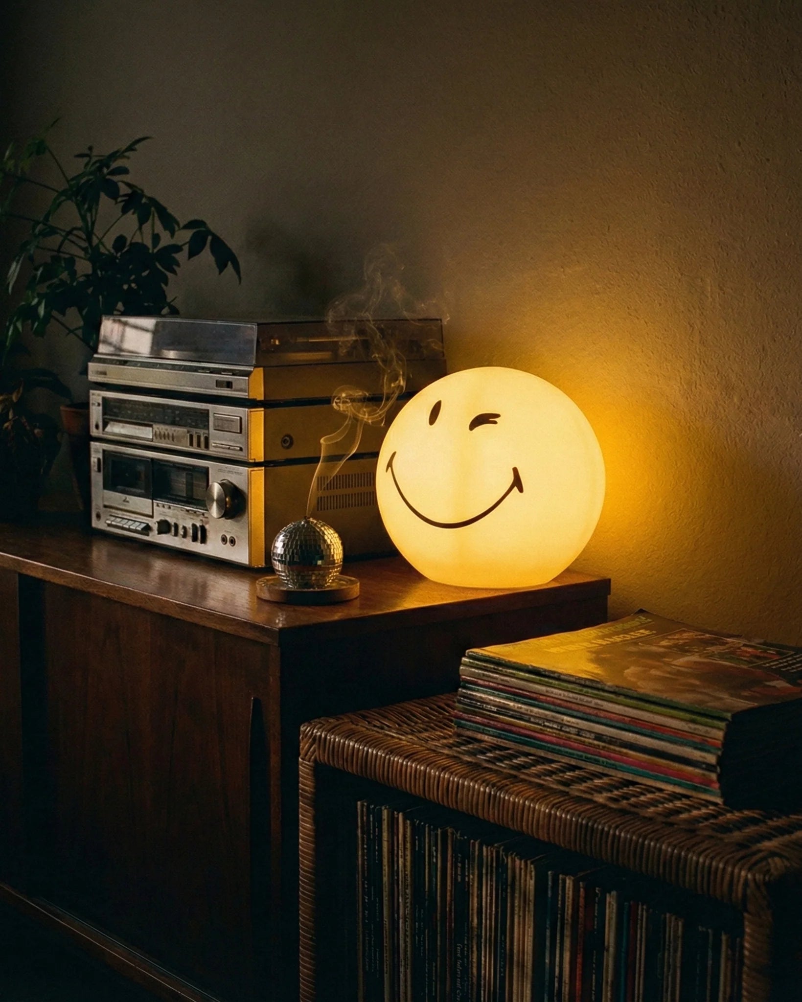 Yellow spherical winking smiley face lamp glowing on white background dopamine decor